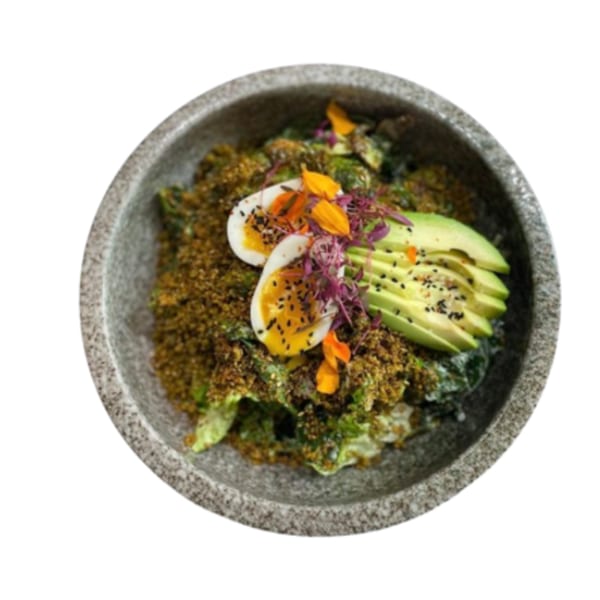 Middle-Eastern dish with roasted greens, za'atar, sliced avocado, soft-boiled eggs, and edible flowers.