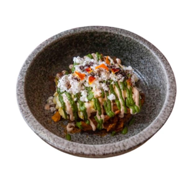 Middle-Eastern dish with green and pink sauces, white cheese, and orange petals in a gray bowl.