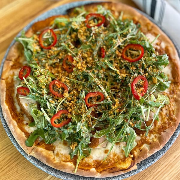 Lulu's Little Kitchen's Middle Eastern pizza, topped with fresh arugula, red peppers, and crispy fried onions.